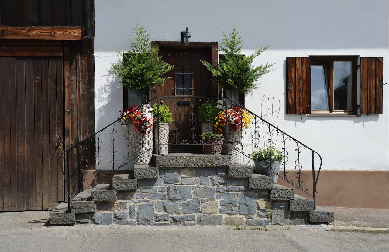 A picturesque rustic entrance showcasing stone steps adorned with vibrant flowers and wooden accents.